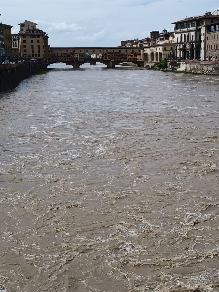 Fast flowing river Arno with view of Ponte Vecchio to the west