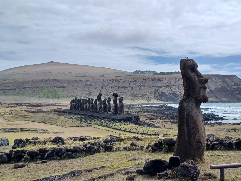 Travelling moai with diuca finch on his head and the fifteen moai at Ahu Tongariki, Rapa Nui.